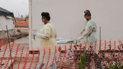 Abakozi batatu bo kwa muganga barimo kugenda imbere mu kigo cyo kuvuriramo ubushita bw'inkende (Mpox) cyo ku bitaro bya kaminuza bya Kamenge, i Bujumbura mu Burundi, ku itariki ya 22 Kanama (8) mu 2024. 