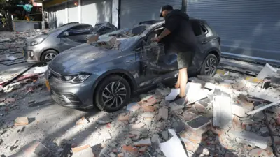 Um homem observa um veículo danificado após um terremoto em Cali, Colômbia, em 10 de agosto de 2026. Um terremoto de magnitude 7,4 abalou grande parte da Colômbia, segundo o Serviço Geológico Colombiano (SGC), e as autoridades relataram danos em várias cidades, incluindo Manizales, Cali e Pereira.