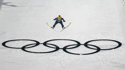 Alman milli kayakçı Katharina Schmid'in kayakla atlayış antrenmanında atlayış sırasında çekilmiş bir fotoğrafı, karın üstünde olimpiyat halkaları var. 