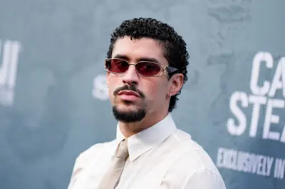 Bad Bunny con gafas rojas y corbata posando ante las cámaras