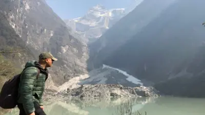 BBC World Service environment correspondent Navin Singh Khadka trekking with mountains visible behind him