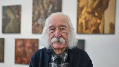 Іван Марчук у картатій сорочці та синьому светрі дивиться прямо