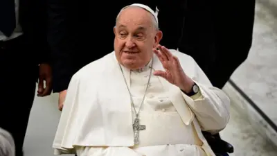 O Papa Francisco acena e sorri para os espectadores enquanto é empurrado22 bet onlineuma cadeira22 bet onlinerodas