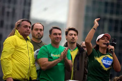 Jair Bolsonaro em um carro de som, ao lado dos filhos Carlos, Flavio e Jair Renan e da esposa Michelle, que discursa ao microfone. Todos usam as cores verde e/ou amarelo. 