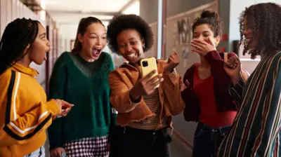 Um grupo de adolescentes na escola fica surpreso com o que um deles mostra no telefone