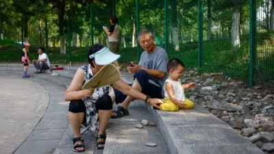 一對老年夫婦在中國北京的一個公園裡照顧幼兒。