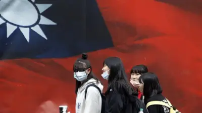 戴著口罩的台灣女生走過中華民國國旗（2021年4月11日資料照片）