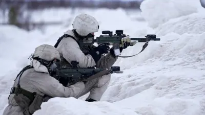 Two members of Sweden's army point guns in the snow