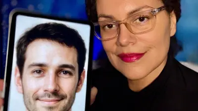 Seorang wanita dengan kacamata bening dan lipstik merah cerah tersenyum saat ia memegang teleponnya ke kamera, memperlihatkan foto teman AI-nya. Di layar telepon terdapat foto seorang pria dengan rambut pendek rapi, janggut tipis, dan mata yang tersenyum.