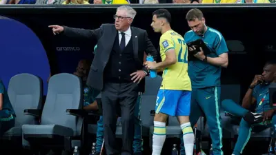 Ancelotti gesticula para Martinelli à beira do gramado; atrás, um assistente olha para uma prancheta.