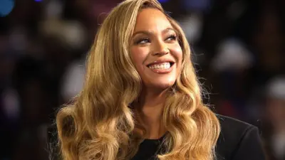 Beyonce Knowles, an African-American woman with shoulder length brown hair, smiles broadly