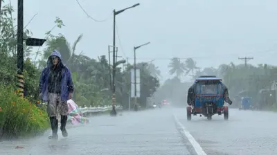 2025年9月22日，受超強颱風「樺加沙」影響，菲律賓卡加延省拉爾鎮（Lal-lo town）出現暴雨，一名男子在路上行走