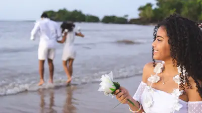 Pessoas pulando onda e depositando flores na praia vestidasaposta ganha onlinebranco