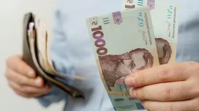 У руках жінки - гаманець і купюри по 100 гривень