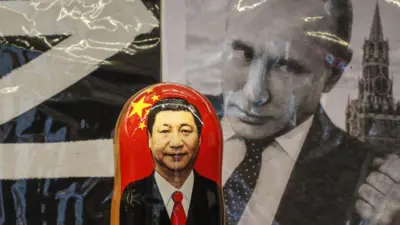 Moskova'da hediyelik eşya satan bir dükkanda Çin Devlet Başkanı Şi Cinping'in fotoğrafını içeren bir matruşka ve arkada Rusya Devlet Başkanı Vladimir Putin'in fotoğrafı