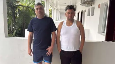 Carlos Alberto Rodelo e Jorge Cubillos em um hotel em Kinshasa, vestidos com camisetas e shorts.