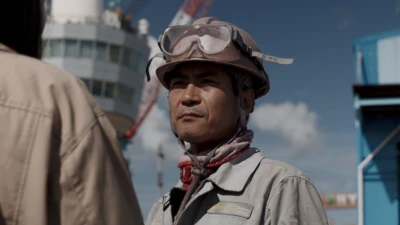 작업복을 입은 남성이 인터뷰어를 바라보고 있다 