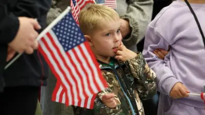 People from the first group of white South Africans granted refugee status in the US hold US flags as they attend a meet and greet event, at Dulles International Airport