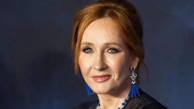 JK Rowling, uma mulher branca de meia idad, de olhos azuis e cabeli vermelho