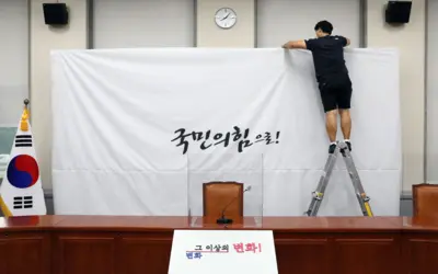 지난 2020년 3월 당명을 '미래통합당'에서 '국민의힘'으로 변경한 국민의힘 담당자가 서울 여의도 국회 당대표회의실의 백드롭 교체 작업을 하고 있다. 배경에는 '국민의 힘으로'라는 글씨가 보인다.