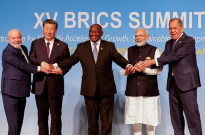 Foto com aperto de mão dos líderes dos Brics. Da esquerda para a direita: Lula, Xi Jinping, Cyrill Ramophosa, Narendra Modi e Sergey Lavrov