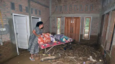 Warga berada di rumahnya yang masih berlumpur akibat banjir bandang di Lapau Munggu, Kuranji, Padang, Sumatera Barat, Selasa (4/8/2026).