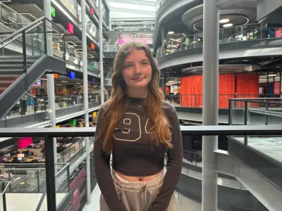 Mia is smiling at the camera. She is stood on the balcony in the ý Wales building in Cardiff