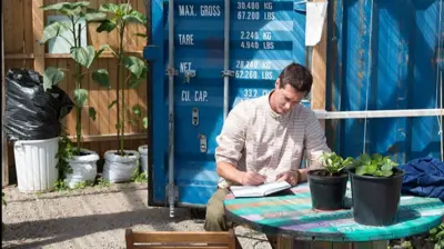Un hombre toma notas en un cuaderno en un jardín en Gotemburgo.