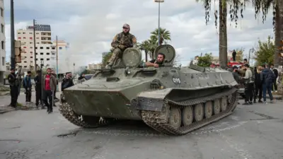 قوات الأمن السورية تقف فوق مركبة عسكرية بينما يتم نشر القوات بعد اندلاع اشتباكات خلال احتجاج قام به أفراد من الطائفة العلوية، 28 ديسمبر 2025.