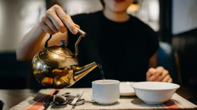 Une femme verse de l'eau chaude dans une tasse