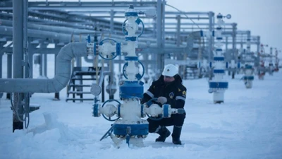 مردی در حال کار روی بخشی از تاسیسات گاز و نفت، فضای کار از برف سفیدپوش شده است