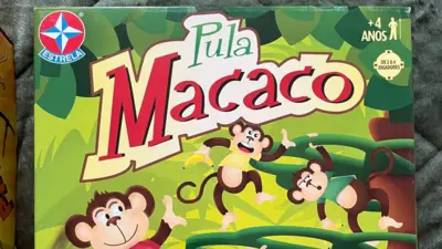 Caixa do jogo “Pula Macaco”, da Estrela, com fundo ilustrado em tons de verde que lembram uma floresta. O nome do brinquedo aparece em destaque no centro, acompanhado de desenhos de macacos pendurados em cipós. No canto superior direito, há a indicação de que o jogo é para crianças a partir de 4 anos e de 2 a 4 jogadores.