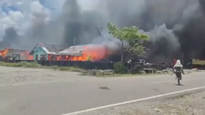 Seorang pria sedang berlari di jalan sambil menengok ke bangunan yang terbakar.