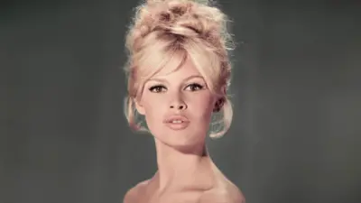 Studio portrait of actor and model Brigitte Bardot wearing a light blue off-the-shoulder dress