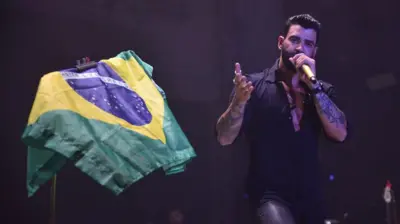Cantor Gusttavo Lima ao ladocbet uabbandeira do Brasil durante show
