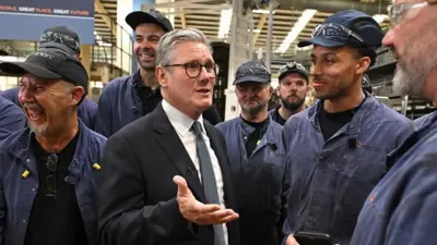 Sir Keir Starmer chats to smiling workers in overalls on a visit to a glass factory in Chester