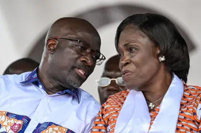 Charles Blé Goudé (à gauche) porte des lunettes parle dans les oreilles de Mme Simone Gbagbo qui a un ruban blanc autour du coup