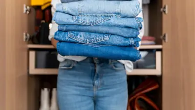زنی تعدادی شلوار جین در دست گرفته