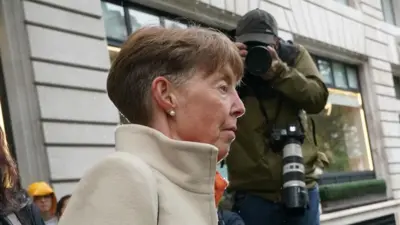 Paula Vennells faces to the side while a photographer is shown behind her, taking a photo