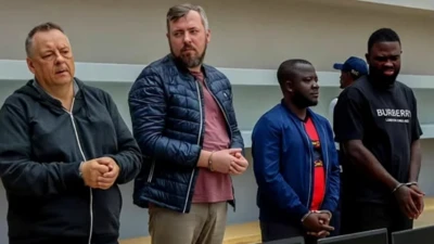 двое европейцев и двое африканцев стоят в наручниках