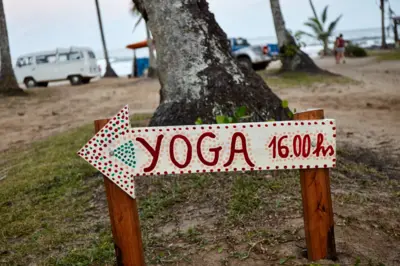 Placa anunciando aula de ioga na praia de Itacaré, na Bahia