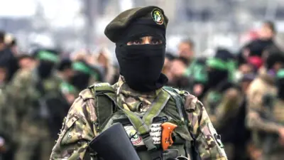 Armed fighters from Hamas' Izz ad-Din al-Qassam Brigades stand guard during the handover of three Israeli hostages to Red Cross representatives in Al Nuseirat refugee camp, central Gaza Strip, 22 February 2025