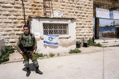 Um jovem soldado israelense guarda a entradaaposta monte carlos futebolum assentamento judeuaposta monte carlos futebolHebron, na Cisjordânia