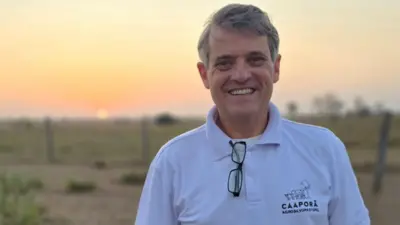 Luís Fernando Laranja Fonseca sorrindo em pasto, com sol se pondo ao fundo