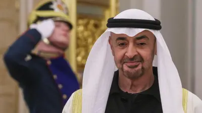 چهره شیخ محمد بن زاید آل نهیان پشت سر او یک افسر گارد در حال سلام نظامی