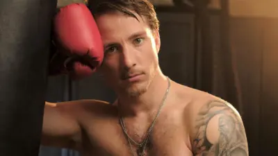 A shirtless man in boxing gloves