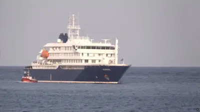 Um barco ao lado do navio de cruzeiro MV Hondius, atingido pelo hantavírus, ancorado no porto de Cabo Verde