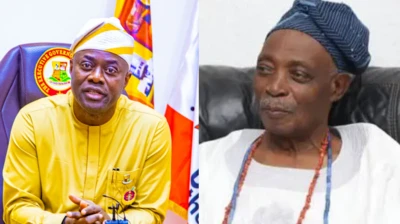 Gómìnà Seyi Makinde sọ aṣọ aláwọ̀ èsúrú, ó ń wo ọ̀ọ́kán, Olubadan ilẹ̀ Ibadan, Ọba Rashidi Ladoja wọ aṣọ funfun ni apá ọ̀tún, ó kó ilẹ̀kẹ̀ sọ̀rùn, ó ń wo ẹ̀gbẹ́