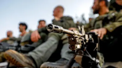 Soldados israelenses sentados ao lado de grande arma