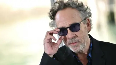 US director Tim Burton looks over his sunglasses as he arrives at the 81st Venice International Film Festival at Venice Lido in August 2024